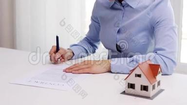 有房子模型和签字笔的女人